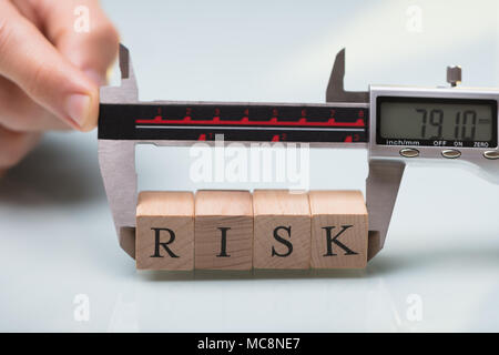 Nahaufnahme einer Person Hand messen Holz- risiko Bausteine mit digitalen elektronischen Messschieber Stockfoto