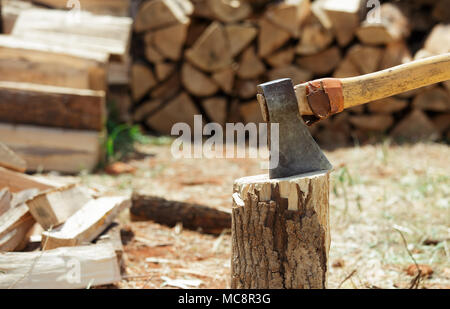 Axt in einem Baumstumpf in der Nähe des Stapels gehackt Brennstämme. Holz splittert. Close-up. Stockfoto