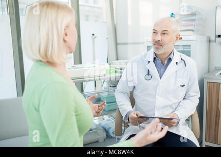 Zuversichtlich Arzt hören auf Ihre Patienten Beschwerden über Gesundheit während des Termins in Kliniken Stockfoto