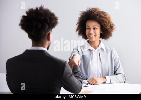 Lächelnden jungen Geschäftsfrau Händeschütteln mit männlichen Bewerber im Büro Stockfoto