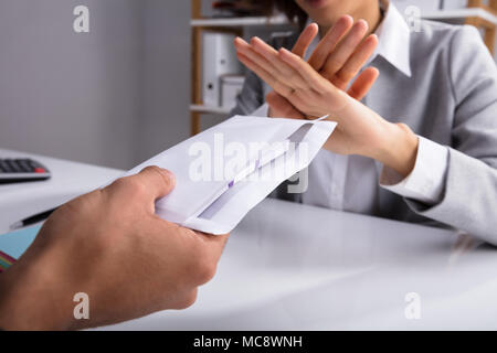 Nahaufnahme der Unternehmer Hand ablehnen, bestechen durch Partner in Umschlag am Arbeitsplatz gegeben Stockfoto