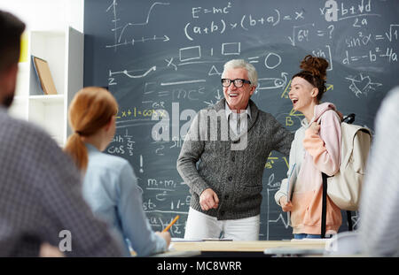 Lachen Lehrer und einem Schüler von blackboard stand vor der groupmates Stockfoto