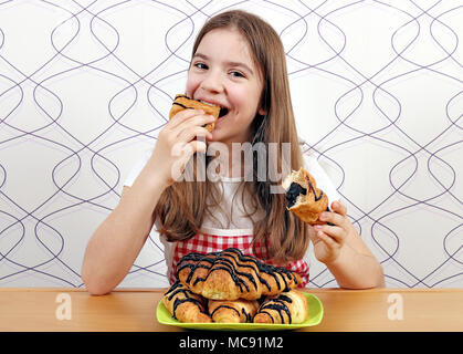 Das kleine Mädchen isst Croissant mit Schokolade Stockfoto