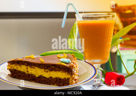 Leckere Schokolade Kuchen mit Eistee Glas- oder Orangensaft auf Tisch verschwommenen Hintergrund. Stockfoto