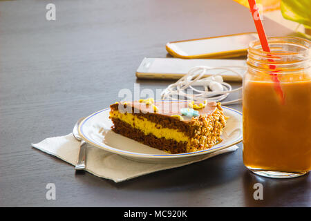 Köstliche Schokolade Kuchen und Smartphone mit Eistee Glas- oder Orangensaft im Coffee Shop in der Tabelle verschwommenen Hintergrund. Stockfoto