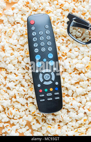 Die vertikale Ansicht der Fernbedienung vom TV und 3D-Brille liegen auf dem Popcorn Stockfoto