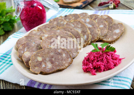 Hausgemachte diätetische Wurst aus der Leber auf einer hölzernen Tisch. Wurst in Stücke geschnitten auf einer Platte mit Meerrettichsauce. Stockfoto