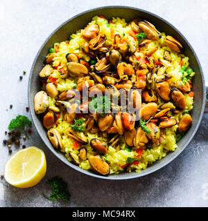 Traditionelle spanische Paella in der Pfanne Reis, Erbsen, Krabben, Muscheln, Tintenfisch auf Hellgrau konkreten Hintergrund. Ansicht von oben, Copyspace. Stockfoto