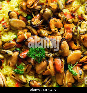 Traditionelle spanische Paella in der Pfanne Reis, Erbsen, Krabben, Muscheln, Tintenfisch auf Hellgrau konkreten Hintergrund. Ansicht von oben, Copyspace. Stockfoto