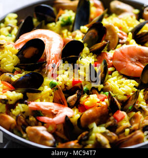 Traditionelle spanische Paella in der Pfanne Reis, Erbsen, Krabben, Muscheln, Tintenfisch auf Hellgrau konkreten Hintergrund. Ansicht von oben, Copyspace. Stockfoto