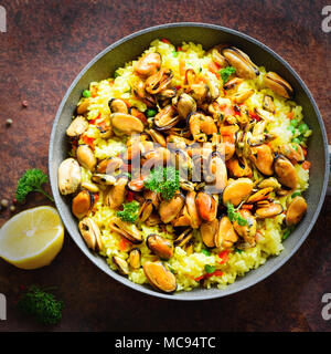 Traditionelle spanische Paella in der Pfanne Reis, Erbsen, Krabben, Muscheln, Tintenfisch auf Hellgrau konkreten Hintergrund. Ansicht von oben, Copyspace. Stockfoto