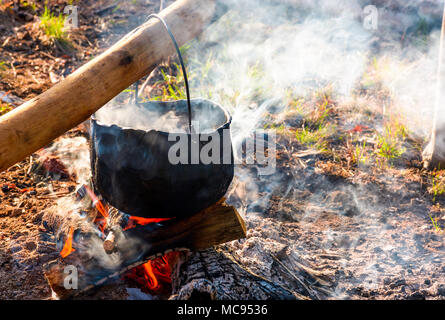 Kessel in den Dampf und Rauch auf offenem Feuer. Kochen im Freien Konzept. altmodische Weise essen zu machen Stockfoto