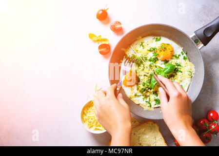 Sonnigen morgen. Frühstück mit Spiegelei in der Pfanne, Kräuter, Gewürze, Tomaten, Käse, Toast, Basilikum auf grauem Beton Stein Hintergrund. Platz kopieren, t Stockfoto