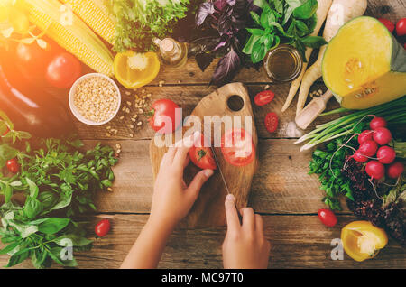 Frau Hände Schneiden von Gemüse auf Holz- Hintergrund. Gemüse Zutaten zum Kochen, Ansicht von oben, Kopieren, flach. Sonnenlicht bokeh Stockfoto