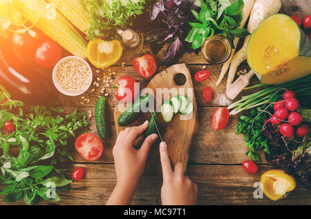 Frau Hände Schneiden von Gemüse auf Holz- Hintergrund. Gemüse Zutaten zum Kochen, Ansicht von oben, Kopieren, flach. Sonnenlicht bokeh Stockfoto