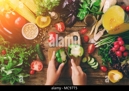 Frau Hände Schneiden von Gemüse auf Holz- Hintergrund. Gemüse Zutaten zum Kochen, Ansicht von oben, Kopieren, flach. Sonnenlicht bokeh Stockfoto