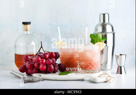 Rosa alkoholfreien Cocktail mit frischen reifen Trauben in einem Shaker mit Eis, Zitrone und Minze. Sommer erfrischenden Drink auf der Tabelle Stockfoto