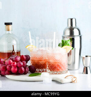 Rosa alkoholfreien Cocktail mit frischen reifen Trauben in einem Shaker mit Eis, Zitrone und Minze. Sommer erfrischenden Drink auf der Tabelle Stockfoto