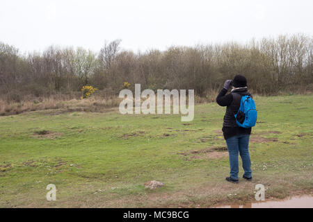 April 2018 - reife Frau, Vogelbeobachtung in einem Park Stockfoto