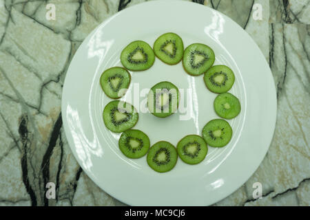 Kiwi Scheiben, ausgebreitet auf einem Schneidebrett in einem Kreis. Hintergrund mit Kiwi scheiben Top View Stockfoto