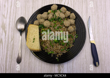 Buchweizen mit Frikadellen und Gemüse auf einem konkreten Hintergrund. Mittagessen für die ganze Familie. Stockfoto