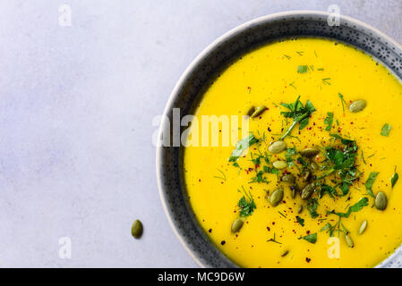 Hell Bio Kürbis, Linsen und Karotten Suppe mit Samen und Kräutern auf hellgrauem Hintergrund. Kopieren Sie Raum, Ansicht von oben Stockfoto