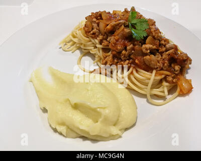 Schweinehack in Tomatensauce Spaghetti mit Kartoffelpüree Stockfoto