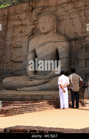 Zwei in Indien oder Sri Lanka Männer vor ein riesiger Sitzender Buddha Statue in der königlichen antiken Stadt Polonnaruwa in Sri Lanka Stockfoto