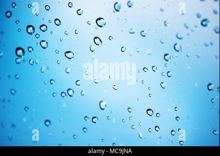 Tropfen Regen auf Glas mit blauem Hintergrund mit lokalen Fokus Stockfoto