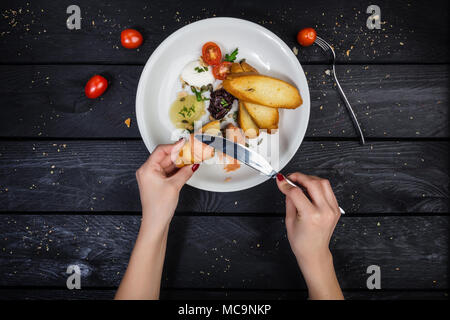 Verschiedene Pasteten mit gebratenen Bruschetta auf dem weißen Teller mit Besteck und Hände auf den Holz- Hintergrund serviert. Ansicht von oben. Stockfoto