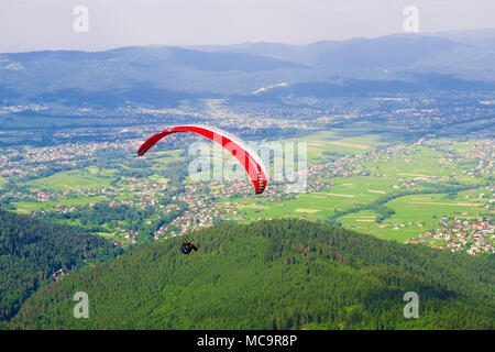 Gleitschirme fliegen über die Felder an einem sonnigen Tag. Stockfoto