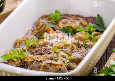 Schweinefleisch in einem Backofen mit Äpfel würfeln, Knoblauch, Kräuter und Zwiebeln Stockfoto