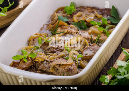 Schweinefleisch in einem Backofen mit Äpfel würfeln, Knoblauch, Kräuter und Zwiebeln Stockfoto