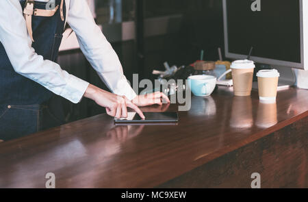 Nahaufnahme barista Kellnerin Verschleiß jean Schürze mit Tablette auf Counter bar lieferbar in Coffee Shop zu prüfen. Essen und Trinken. Technologie lifestyle Stockfoto