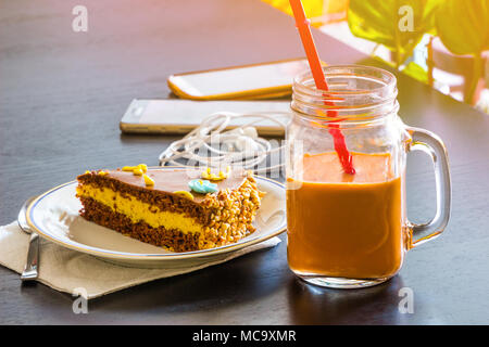 Köstliche Schokolade Kuchen und Smartphone mit Eistee Glas- oder Orangensaft im Coffee Shop in der Tabelle verschwommenen Hintergrund. Stockfoto