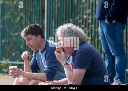 Zwei Unterstützer von Warrington Stadt essen einen Snack in der Halbzeit des Spiels an Throstle Nest, Farsley während des Spiels zwischen Warrington Town FC und Farsley Celtic am 14. April 2018 wo Warrington gewonnen 2 - 0 Credit: John Hopkins/Alamy leben Nachrichten Stockfoto