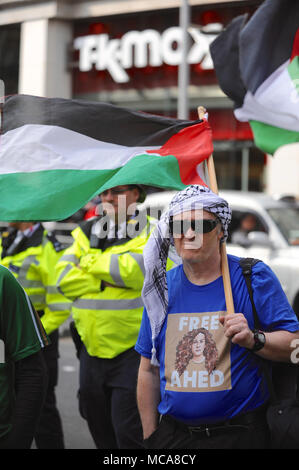 London, Großbritannien, 14. April 2018 trägt eine Kufiya und halten eine palästinensische Flagge zu einem palästinensischen Rechte demo gegenüber der israelischen Botschaft in Kensington, London, Vereinigtes Königreich. Die etwas rauhe Demonstration war recht gut mit rund 60 anwesenden Personen unterstützt. Es war infolge der jüngsten Gewalt zwischen den beiden Seiten aufgerufen, über die anhaltenden Spannungen im Gazastreifen zu protestieren. London, Großbritannien, 14. April 2018 sammeln von Fünf pro-israelischen Demonstranten gehechelt, die Demonstration von der anderen Seite der Straße. Quelle: Michael Preston/Alamy leben Nachrichten Stockfoto