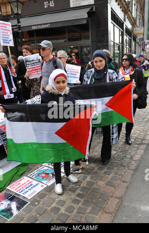 London, Großbritannien, 14. April 2018 muslimische Mädchen und ihre Mutter holding Palästinensischen Fahnen auf die palästinensischen Rechte demo gegenüber der israelischen Botschaft in Kensington, London, Vereinigtes Königreich. Die etwas rauhe Demonstration war recht gut mit rund 60 anwesenden Personen unterstützt. Es war infolge der jüngsten Gewalt zwischen den beiden Seiten aufgerufen, über die anhaltenden Spannungen im Gazastreifen zu protestieren. London, Großbritannien, 14. April 2018 sammeln von Fünf pro-israelischen Demonstranten gehechelt, die Demonstration von der anderen Seite der Straße. Quelle: Michael Preston/Alamy leben Nachrichten Stockfoto