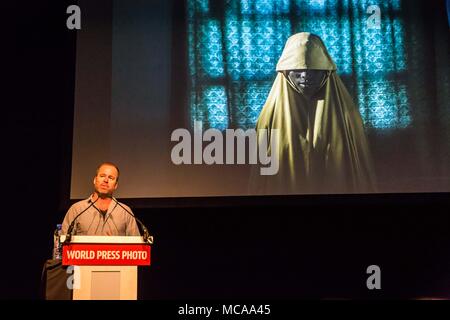 Amsterdam, Niederlande. 14 Apr, 2018. ADAM FERGUSON gibt eine kurze Präsentation auf der World Press Photo Festival am Samstag, 14. April 2018 in Amsterdam, Niederlande. Eines seiner Bilder von seinem Boko Haram Survivor Series hinter ihm gezeigt. Ferguson erste Anerkennung für seine Arbeit im Jahr 2009 gewonnen, wenn er auf eine nachhaltige Umfrage der US-begann-geführten Krieg in Afghanistan. Diese Arbeit erhielt Auszeichnungen von World Press Photo Credit: ZUMA Press, Inc./Alamy leben Nachrichten Stockfoto