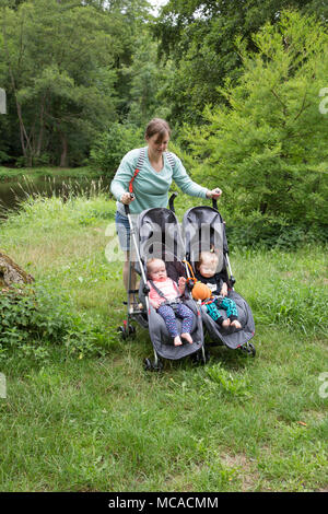 Junge Mutter schiebt einen Doppelbuggy im Urlaub mit Zwillingen. Stockfoto