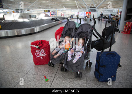 10 Monate altes Baby Zwillinge in einem Doppelbuggy unbeaufsichtigt am Stansted Airport, Großbritannien Stockfoto