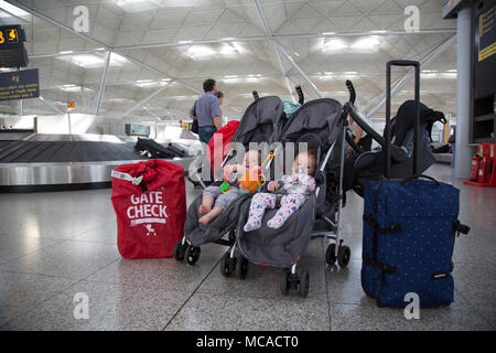 10 Monate altes Baby Zwillinge in einem Doppelbuggy unbeaufsichtigt am Stansted Airport, Großbritannien Stockfoto