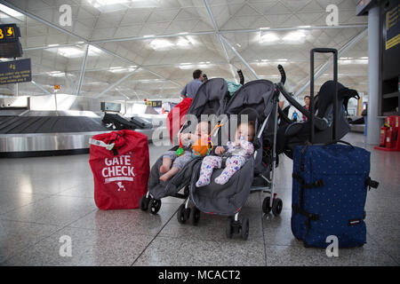 10 Monate altes Baby Zwillinge in einem Doppelbuggy unbeaufsichtigt am Stansted Airport, Großbritannien Stockfoto