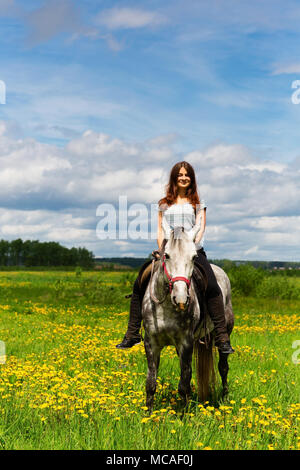 Frau reiten auf graues Pferd im Bereich Stockfoto