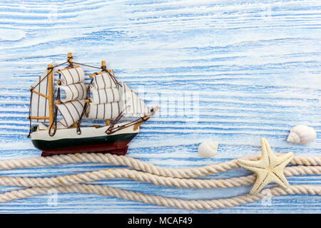 Schiff mit Muscheln und Seil auf Blau Holz- Hintergrund. Meer Thema Dekorationen Stockfoto