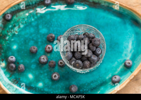 Das gesunde Essen. Blaubeeren in crystall Glas auf Türkis Keramikplatte gestellt. Draufsicht auf die Tiefenschärfe. Stockfoto