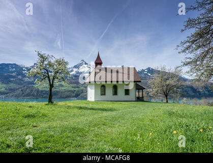 Kleine weiße Kapelle in einer wunderschönen Berglandschaft im Frühjahr mit einem türkisfarbenen See hinter Stockfoto