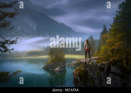 Schöne Sicht auf den See - landcape Laghi di Fusine auf idyllischen misty Dawn mit Frau beobachten Landschaft in Ehrfurcht. Stockfoto
