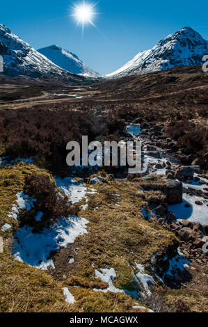Die atemberaubende Aussicht auf die schottischen Highlands - eine helle Sonne strahlt auf die Berge von Glencoe Stockfoto