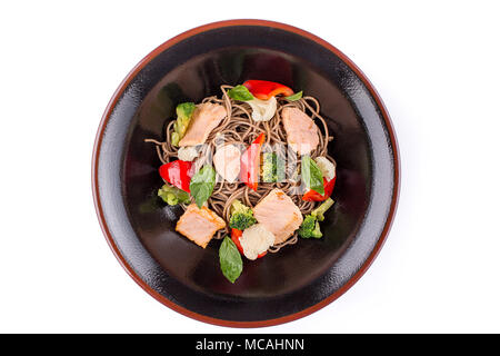 Buchweizen Nudeln mit Lachs unter teriyaki Sauce, auf weißem Hintergrund. Buchweizen Nudeln in eine schwarze Platte. Platte der ungewöhnliche Form. Stockfoto